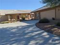 A view of the driveway and the landscaped yard leading to an attached garage and stucco house at 1211 Bourbon St, Pahrump, NV 89048