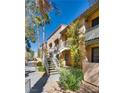 A charming condo exterior with walkways, stairs, and mature trees against a blue sky at 5138 S Jones Blvd # 207, Las Vegas, NV 89118
