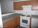 A bright kitchen featuring wood cabinets, gray countertops, and a white gas range at 833 Aspen Peak Loop # 2614, Henderson, NV 89011