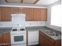 A bright kitchen featuring wood cabinets, a white gas range, a stainless steel sink and dishwasher at 833 Aspen Peak Loop # 2614, Henderson, NV 89011