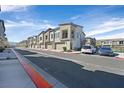A row of modern townhomes feature attached garages, set along a tree-lined street with parked cars at 7304 N Decatur Blvd # 6, North Las Vegas, NV 89131