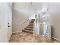 Bright foyer with tile flooring leads to an upper level with carpeted stairs and white railings at 304 Jolly January Ave, Las Vegas, NV 89183