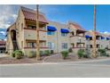 View of the condo complex featuring red tile roofing, blue awnings, and desert landscaping at 4140 Gannet Cir # 255, Las Vegas, NV 89103