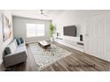 Staged living room features neutral colors, wood floors, a modern entertainment center, and natural light from the window at 45 Maleena Mesa St # 327, Henderson, NV 89074