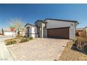 Inviting single-story home featuring a neatly landscaped front yard and brick-paved driveway leading to a two-car garage at 4743 S Sungold St, Pahrump, NV 89061