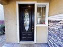 Elegant front door with decorative glass, enhanced by natural light and stylish stone detailing at 5361 Candlespice Way, Las Vegas, NV 89135