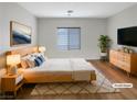 Cozy bedroom featuring a natural wood bed frame, neutral bedding, and a modern dresser, all on wood floors at 6228 Grace Mountain St, Las Vegas, NV 89115