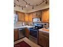 Well-lit kitchen featuring stainless steel appliances, warm wood cabinets, and tiled countertops at 741 Bourbon St # E3, Pahrump, NV 89048