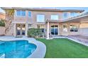 Backyard view shows a pool, synthetic grass, and covered patio with shade at 7520 Jacaranda Bay St, Las Vegas, NV 89139
