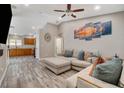 Open-concept living room with a comfortable sectional sofa, ceiling fan, and decorative wall art at 9292 Vervain Ct, Las Vegas, NV 89149