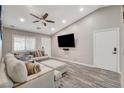 Spacious living room with a modern sectional, ceiling fan, and a mounted flat-screen television at 9292 Vervain Ct, Las Vegas, NV 89149