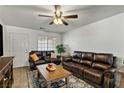 Comfortable living room featuring leather sofas, ceiling fan, and a large window providing natural light at 2773 Chetco River St, Laughlin, NV 89029