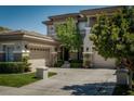 A front view of a stucco home featuring multi-car garage, manicured lawn, and mature trees at 504 Pinnacle Heights Ln, Las Vegas, NV 89144