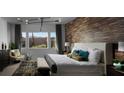 Serene main bedroom showcasing a wood-accent wall, stylish lighting fixture, and a comfortable sitting area by the windows at 5725 N Conquistador St, Las Vegas, NV 89149