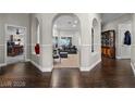 Grand foyer with arched entryways, dark hardwood floors, and an inviting view into the living area at 7944 Marbella Cir, Las Vegas, NV 89128