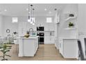 Modern white kitchen with stainless steel appliances, a center island, and open layout to the dining area at 10801 Clarion Ln, Las Vegas, NV 89134