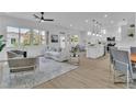 Open-concept living area with large windows, wood flooring, modern furnishings, and a seamless flow to the kitchen at 10801 Clarion Ln, Las Vegas, NV 89134