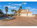 Elegant two-story home with a fountain, circular driveway and lush palm trees at 117 Milton Ct, Boulder City, NV 89005