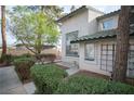 Stucco townhome with lush landscaping, showcasing its well-maintained exterior and curb appeal at 2430 Old Forge Ln # 106, Las Vegas, NV 89121