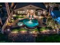 An aerial nighttime view of a backyard featuring a sparkling pool, spa, and beautifully landscaped grounds at 2824 Soaring Peak Ave, Henderson, NV 89052