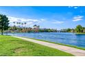 Scenic view of the lake and a grassy pathway with palm trees and a building on the opposite side of the water at 3125 N Buffalo Dr # 1136, Las Vegas, NV 89128