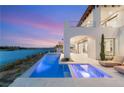 An outside view of an illuminated pool area with lake view and an incredible sunset in the background at 32 Grand Corniche Dr, Henderson, NV 89011
