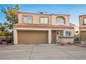 Beige two-story home with a two-car garage, terracotta tile roof, and manicured landscaping at 3331 Cheltenham St, Las Vegas, NV 89129