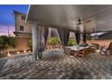 Covered patio featuring a dining table, ceiling fans, outdoor lighting, and privacy curtains at 9783 Hawk Crest St, Las Vegas, NV 89141