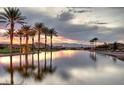 Reflective community pond at sunset with mature palms and mountain backdrop at 30 Strada Di Villaggio # 118, Henderson, NV 89011