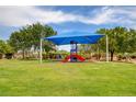 Bright and colorful community playground with a slide set under a shaded canopy on green lawn at 4225 Ponce Royal Ave, North Las Vegas, NV 89031