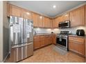 Well-lit kitchen featuring stainless steel appliances, wood cabinets, and tile flooring at 6030 Hidden Summit St, North Las Vegas, NV 89031