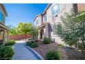 Inviting townhome with landscaped front yard, decorative rock, walkway, and covered entry with stone accents at 8487 Insignia Ave # 105, Las Vegas, NV 89178