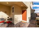 Welcoming front porch with cozy seating area, colorful potted plants, and a charming orange front door at 996 Cetona Ct, Henderson, NV 89011