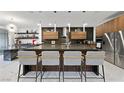 Sleek kitchen with a large island, modern stools, stainless steel appliances, and unique pendant lighting at 2819 Queens Courtyard Dr, Las Vegas, NV 89109