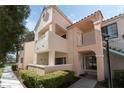 Charming condo featuring a light pink facade, balcony, and well-maintained landscaping at 4861 S Torrey Pines Dr # 106, Las Vegas, NV 89103