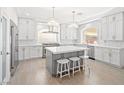Bright kitchen features white cabinetry, an island, modern appliances, three barstools, and wooden floor at 6335 Mount Eden Ave, Las Vegas, NV 89139