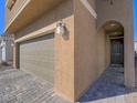 Inviting home exterior with a spacious two-car garage and textured walls and a quaint, arched doorway at 10279 Fragrant Apple Ct, Las Vegas, NV 89141