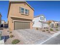 Two-story home featuring a brown stucco exterior, a two-car garage, and desert landscaping at 10279 Fragrant Apple Ct, Las Vegas, NV 89141