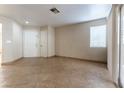 An empty living room with tan tile flooring, a large window and two interior doors at 1560 Jamielinn Ln # 101, Las Vegas, NV 89110