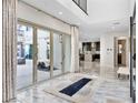 Bright entryway featuring marble floors and glass doors that open to an outdoor space, with a modern kitchen in the background at 12 Olympia Chase Dr, Las Vegas, NV 89141