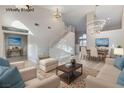 Bright, airy living room with a staircase, modern chandelier, dining area, and neutral decor at 1700 Wandering Winds Way, Las Vegas, NV 89128