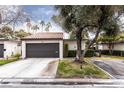 Home with a grey garage door, lawn, mature trees, and exterior shrubbery at 3440 Pino Cir, Las Vegas, NV 89121