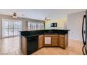A kitchen features a breakfast bar, oak cabinets, black appliances and connects to a living space with a ceiling fan at 7567 Wingspread St, North Las Vegas, NV 89084