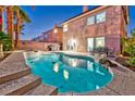 Inviting backyard pool featuring tanning ledge, palm trees, and patio seating at 7581 Slipstream St, Las Vegas, NV 89139