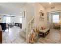 Inviting foyer with light wood-look floors and staircase, complemented by a stylish bench and decor at 8432 Alder Rain St, Las Vegas, NV 89113