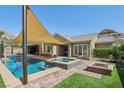 Backyard oasis with a refreshing pool, spa, fire pit, and covered patio for entertaining at 11181 Luna Blanca Dr, Las Vegas, NV 89138