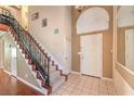 Inviting foyer featuring tile flooring, a staircase, and a coat closet at 1209 Shifting Sands Dr, Las Vegas, NV 89108