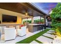 Outdoor kitchen and entertainment area with bar seating, a grill, and a mounted television at 3929 Reyes Ave, Las Vegas, NV 89141