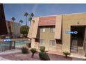 A low-angle exterior view of a tan apartment complex near a community pool at 4411 Alexis Dr # 444, Las Vegas, NV 89103