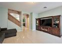 Bright and spacious living room with tile flooring, entertainment center, and stairway access at 6891 Nickel Mine Ave, Las Vegas, NV 89122